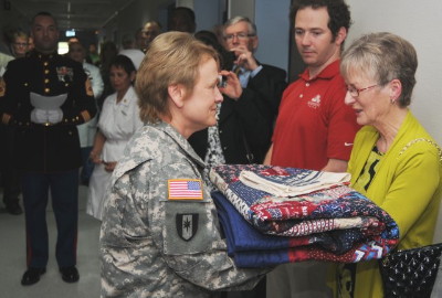 Maria Fox-Meehan receives a handmade quilt of valor during the dedication ceremony of The Thomas Meehan Suite